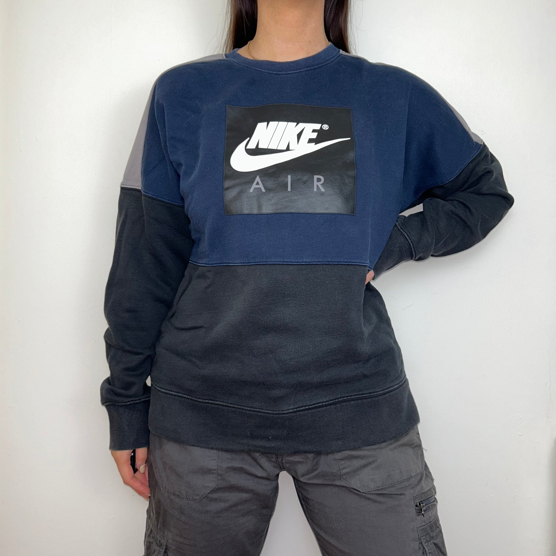 black and navy sweatshirt with white nike logo shown on a model wearing grey cargo trousers