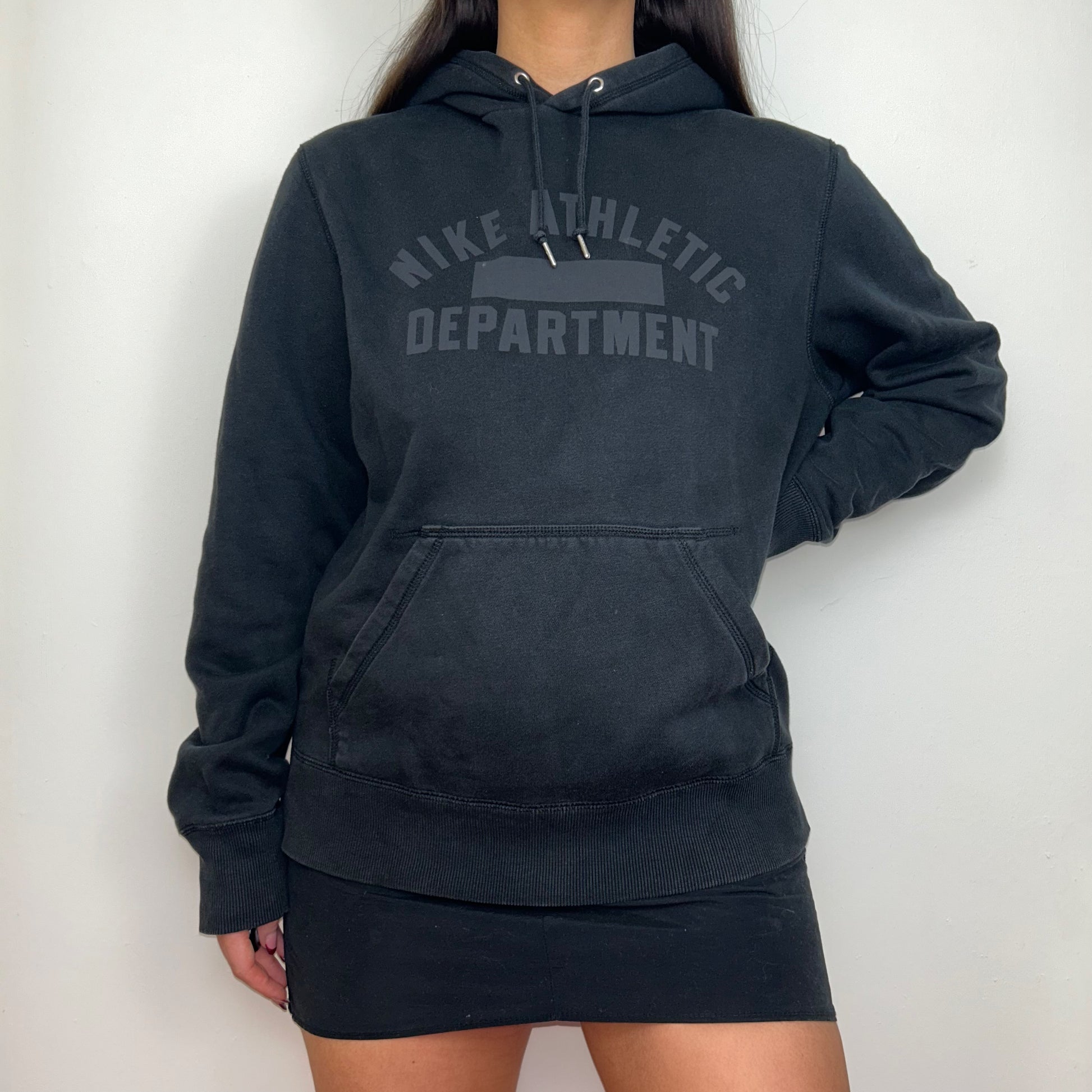 black hoodie with grey nike athletic logo shown on a model wearing a black mini skirt