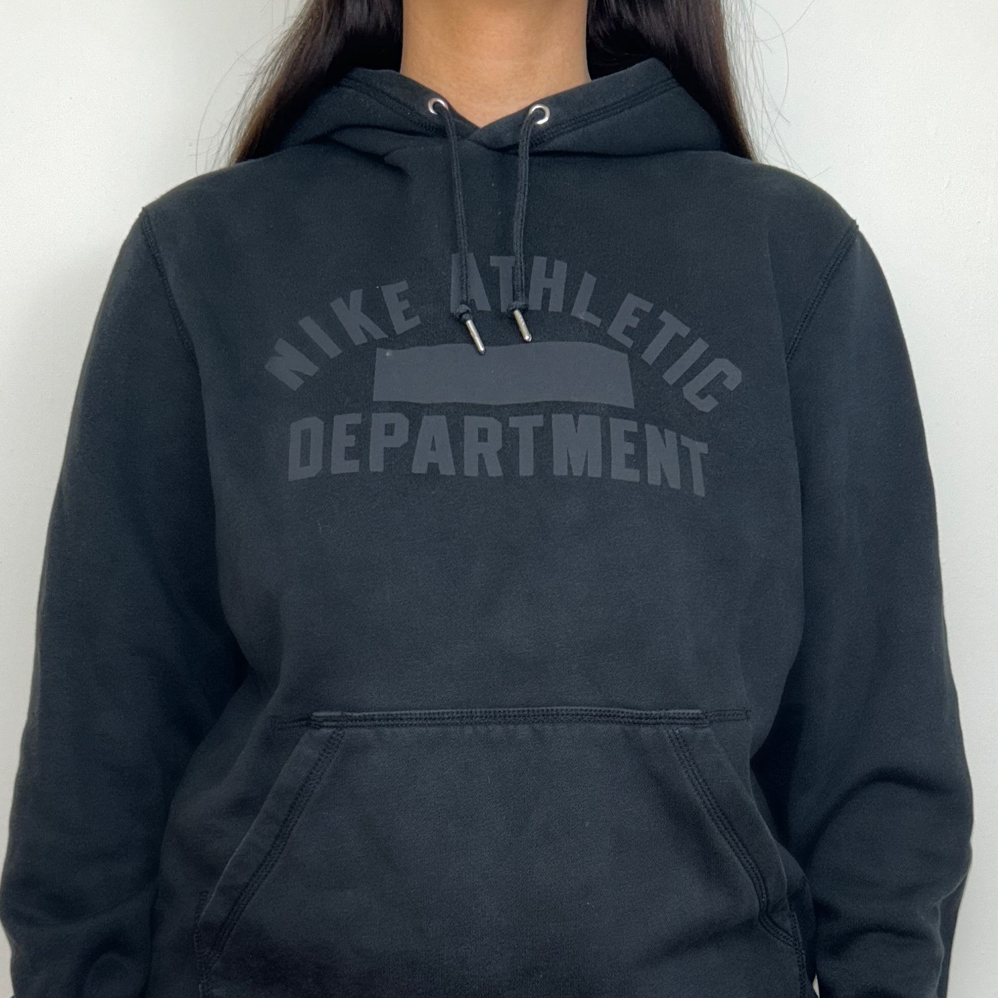 close up of black hoodie with grey nike athletic logo shown on a model
