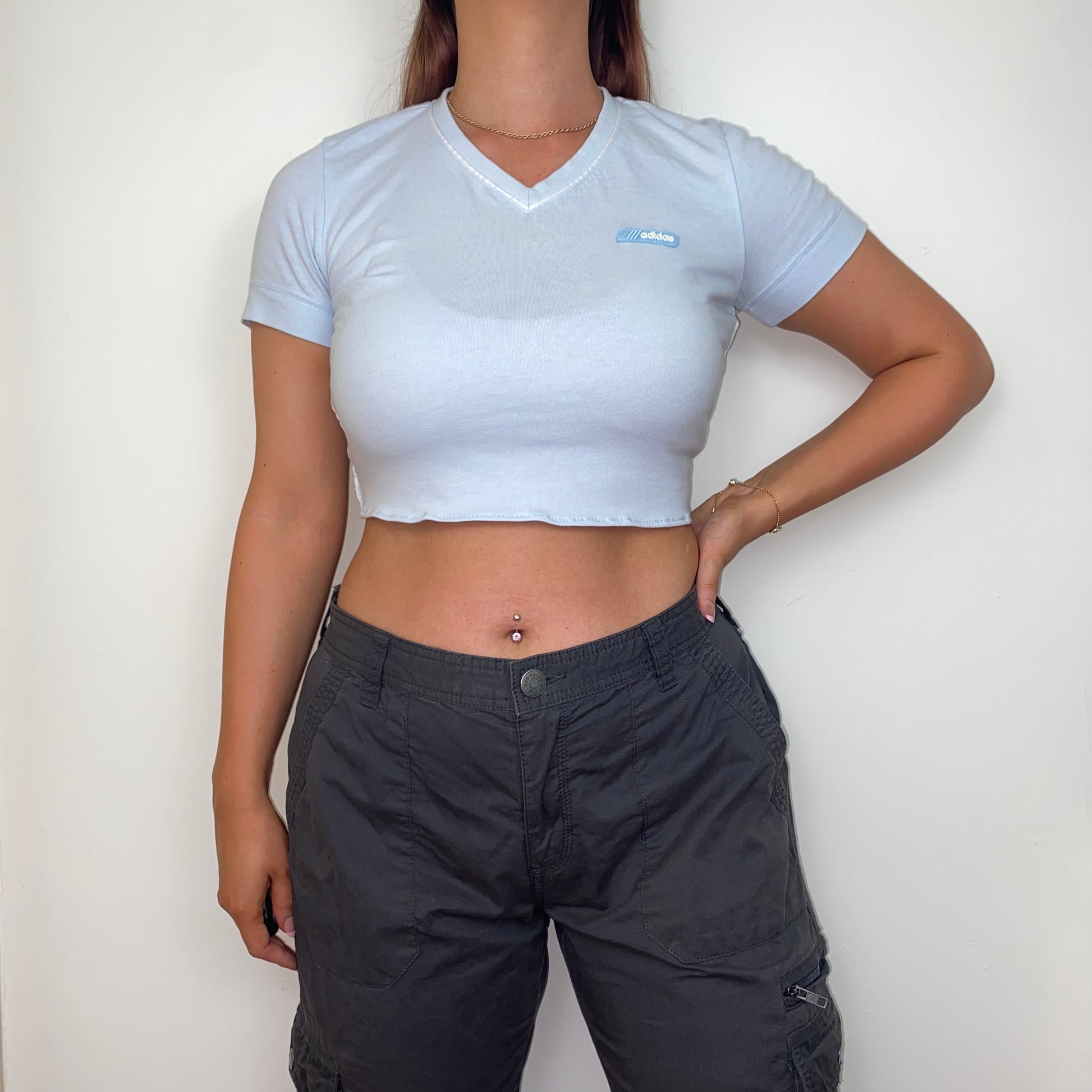 light blue short sleeve crop top with white adidas logo shown on a model wearing grey trousers