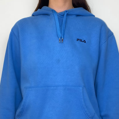 close up of blue hoodie with black fila logo shown on a model