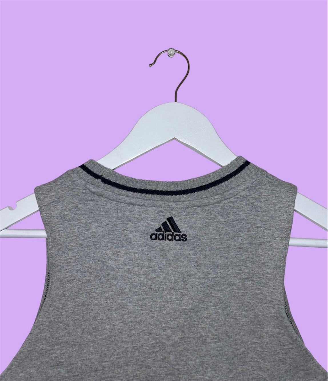 back of grey sleeveless crop top with small adidas logo shown on a lilac background
