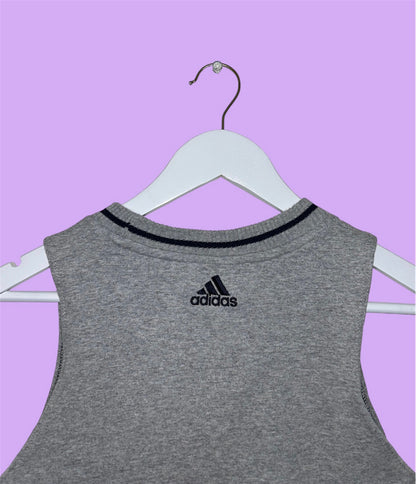 back of grey sleeveless crop top with small adidas logo shown on a lilac background