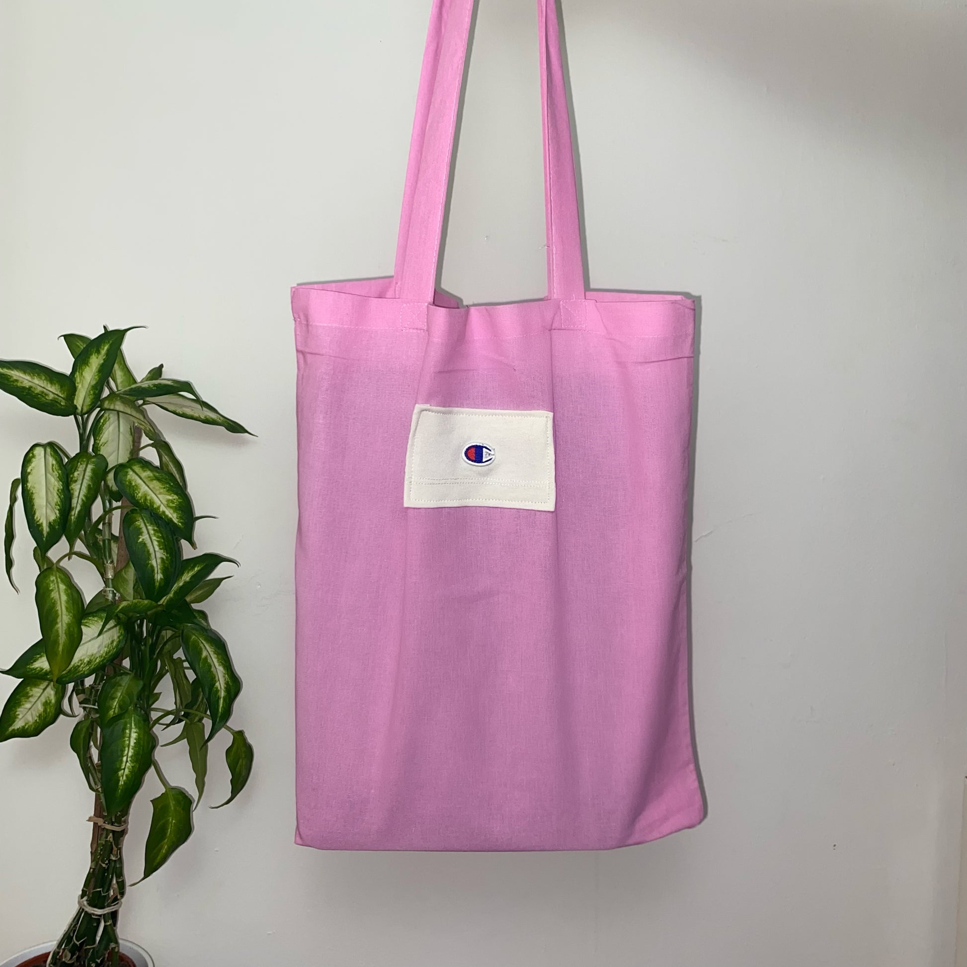 light pink tote bag with blue and red champion logo