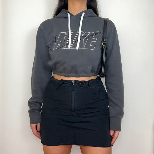 dark grey cropped hoodie with black and white nike logo shown on a model wearing a black mini skirt and black shoulder bag