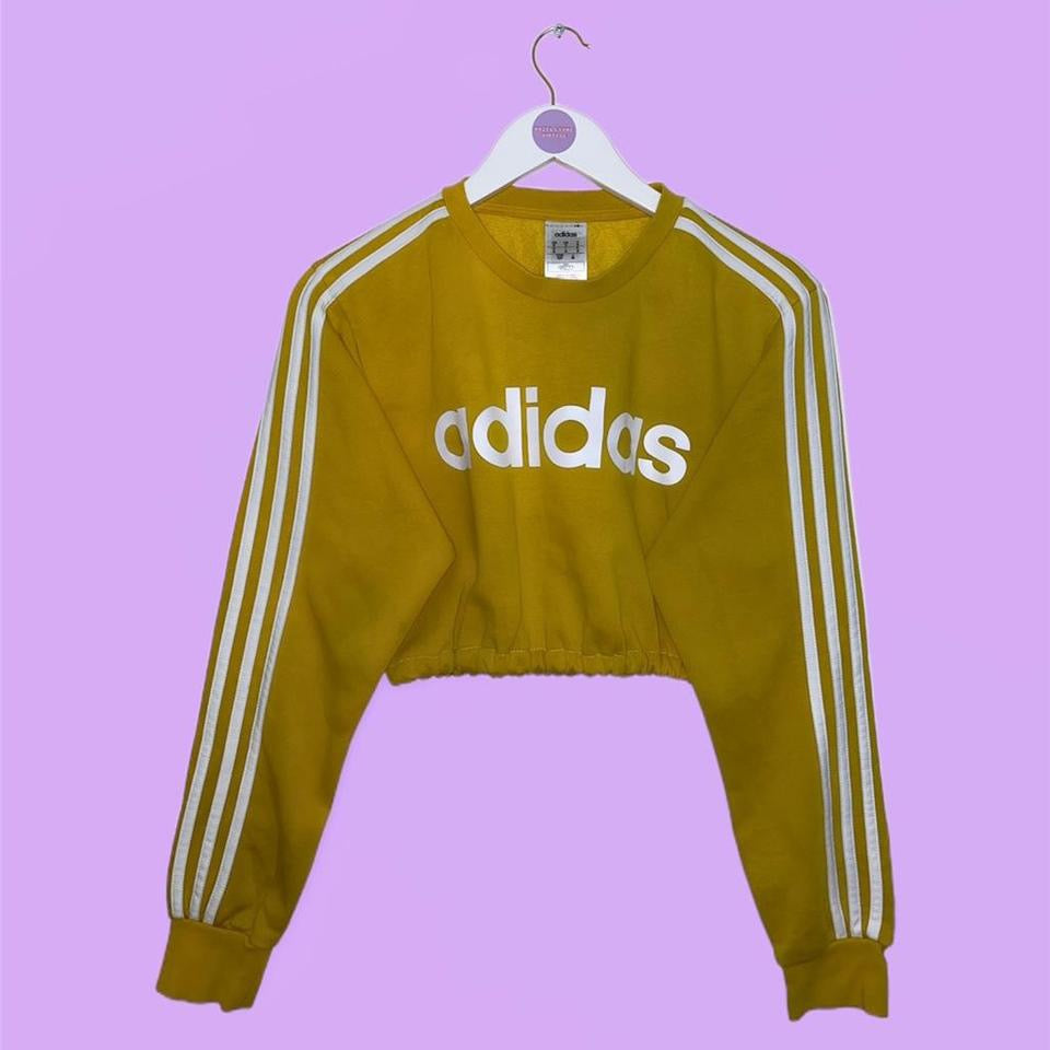 yellow cropped sweatshirt with white adidas logo shown on a lilac background