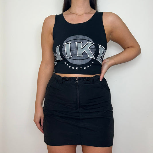 black sleeveless crop top with grey nike logo shown on a model wearing a black cargo skirt