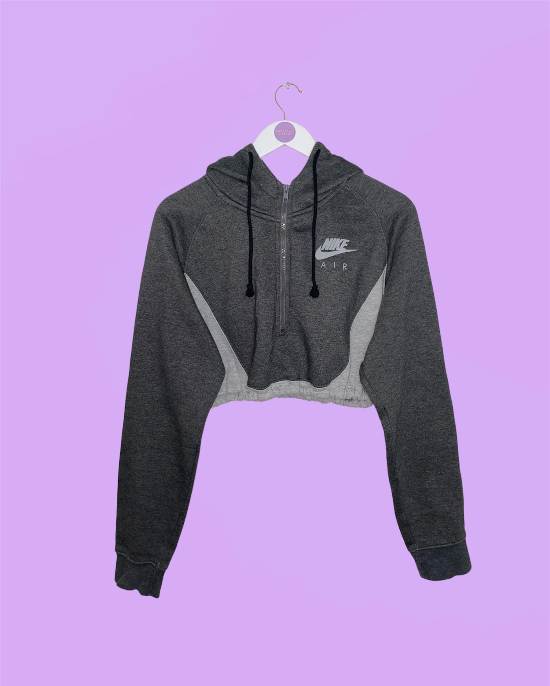 grey 1/4 zip cropped hoodie with nike air logo shown on a white clothes hanger on a lilac background