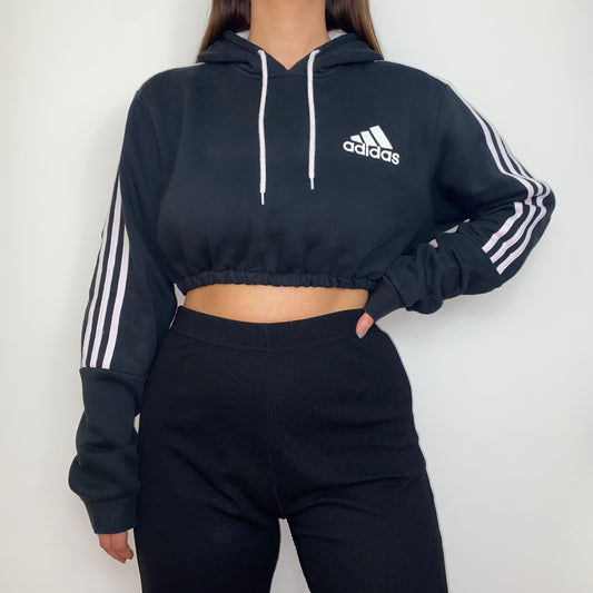 black cropped hoodie with white adidas logo shown on a model wearing black trousers