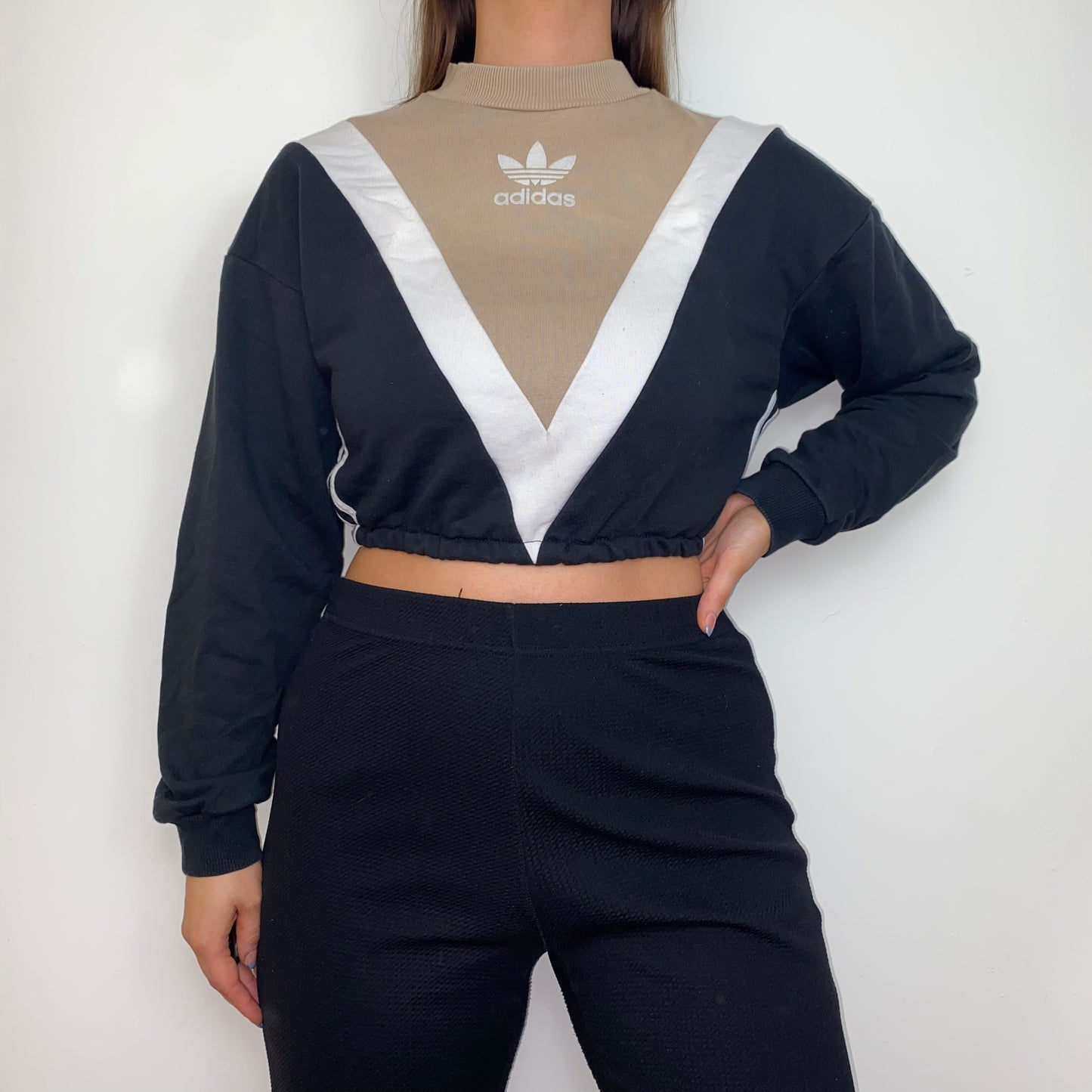 black and beige cropped hoodie with white adidas logo shown on a model wearing black trousers