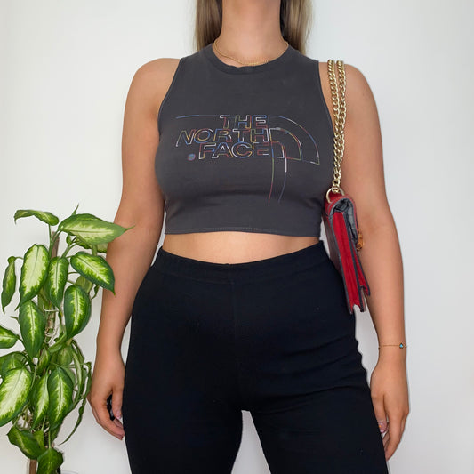 grey sleeveless crop top with the north face logo shown on a model wearing a gold chain red shoulder bag