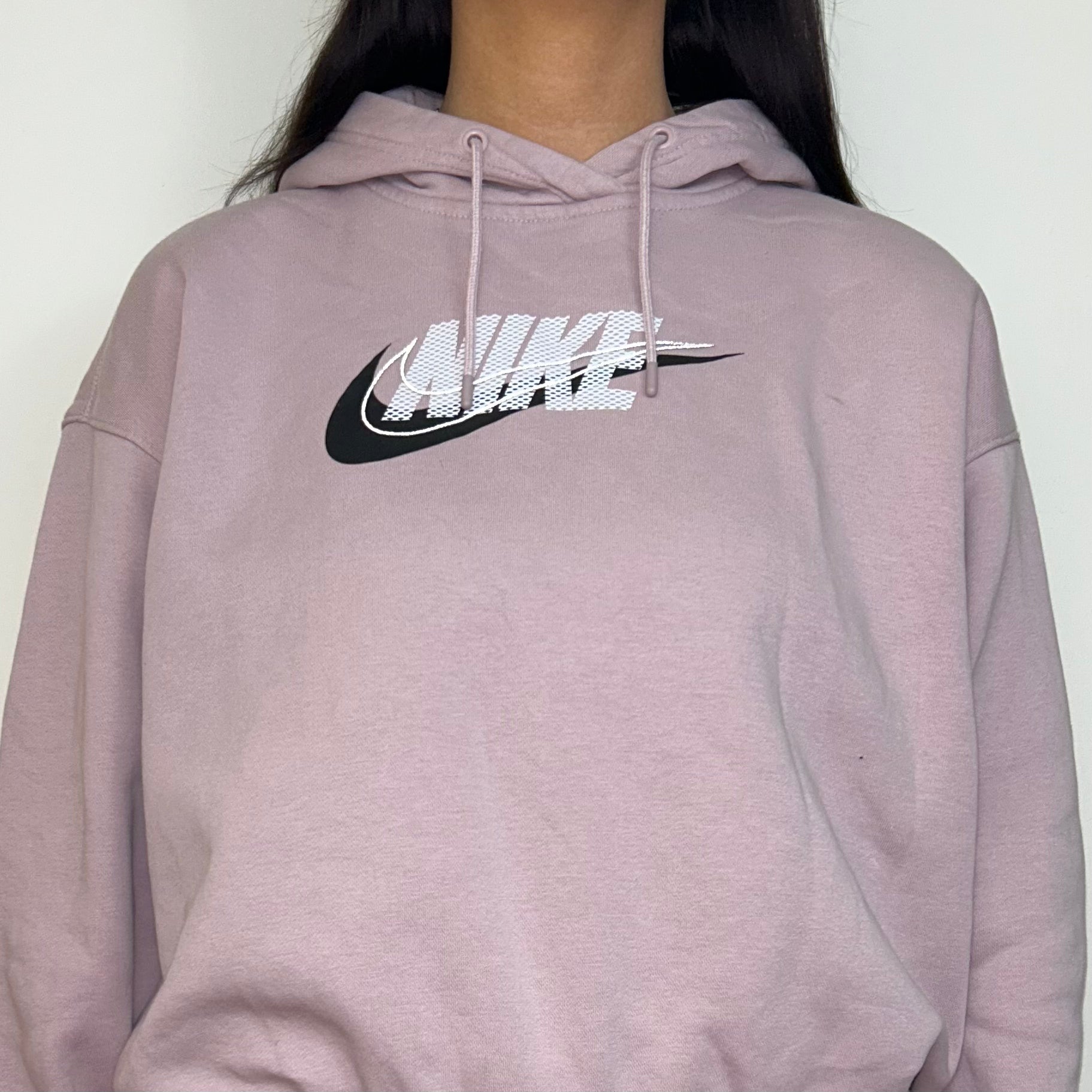 close up of pink hoodie with white and black nike logo shown on a model 