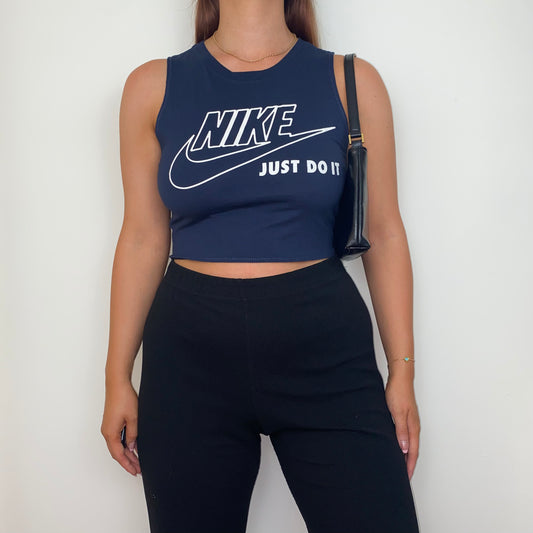 navy sleeveless crop top with white nike logo shown on a model wearing black trousers and a black shoulder bag