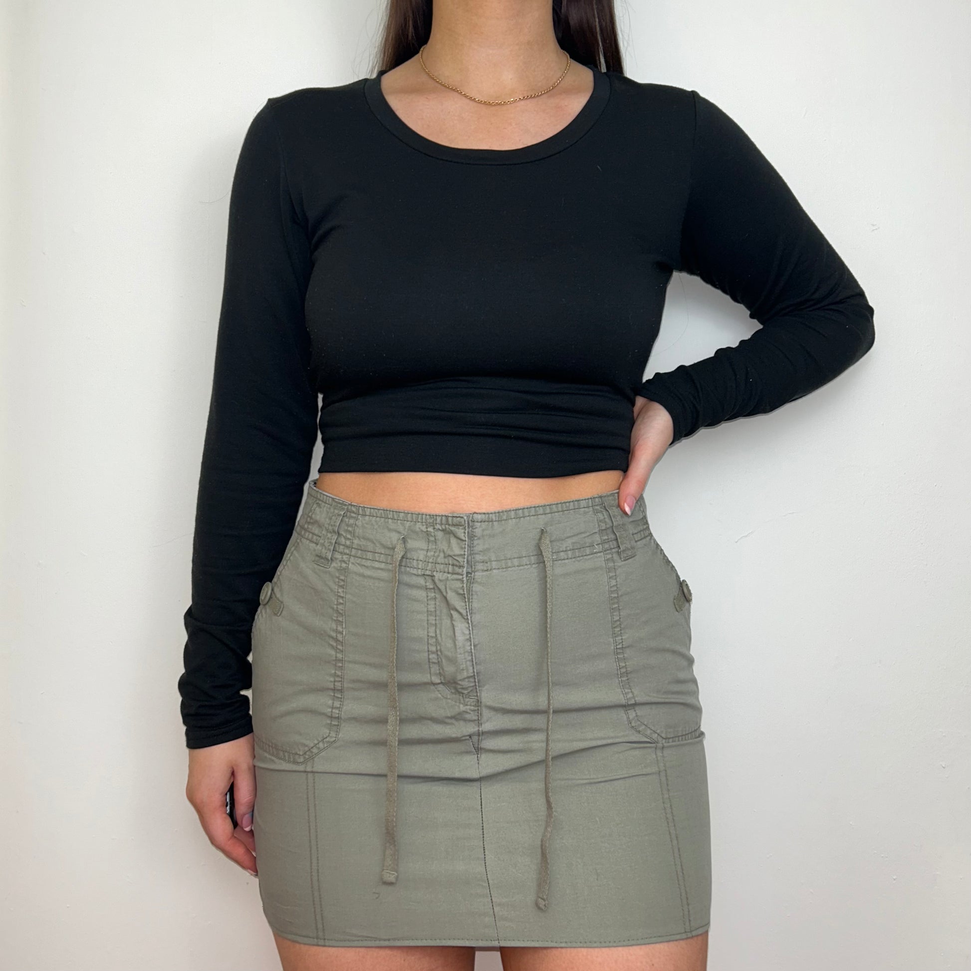 khaki grey mini cargo skirt shown on a model wearing a black long sleeve top