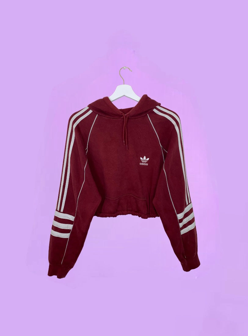 burgundy cropped hoodie with white adidas logo shown on a lilac background