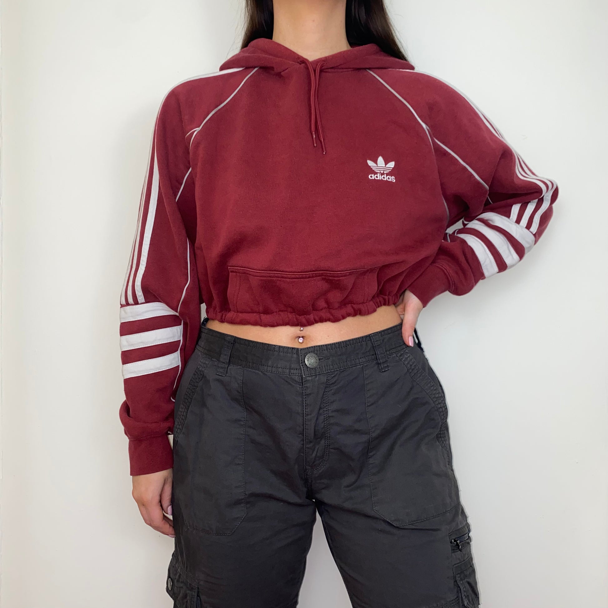 burgundy cropped hoodie with white adidas logo shown on a model wearing grey cargos