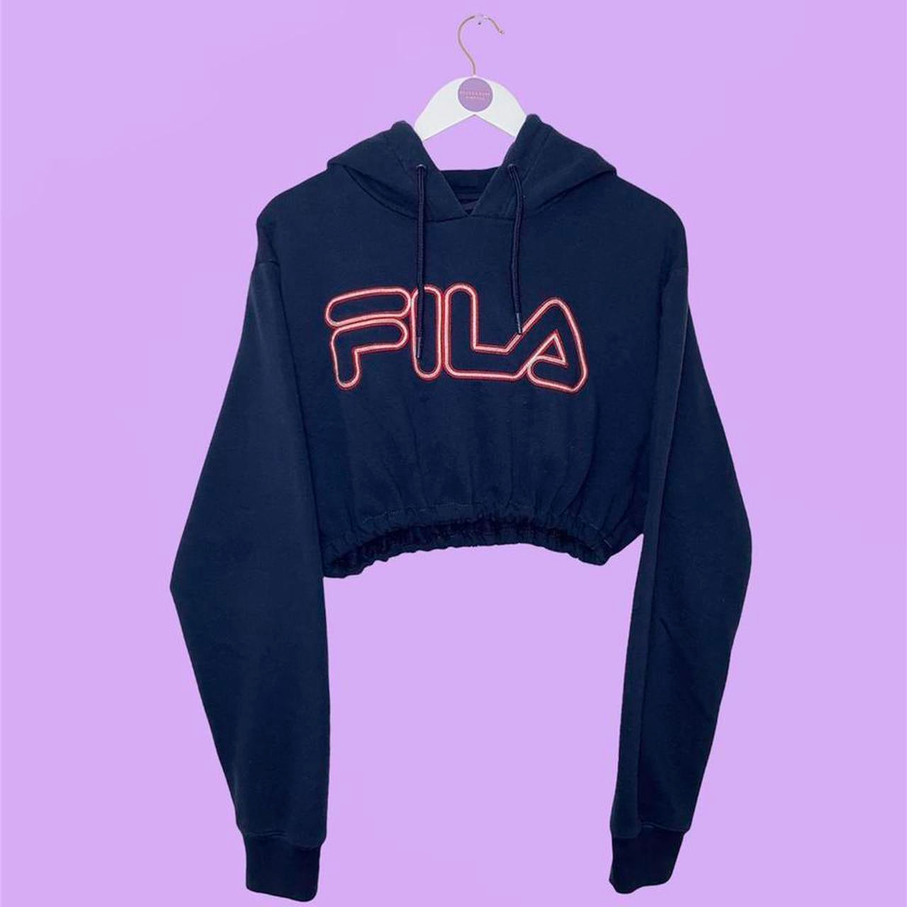 navy cropped hoodie with red big text fila logo shown on a lilac background