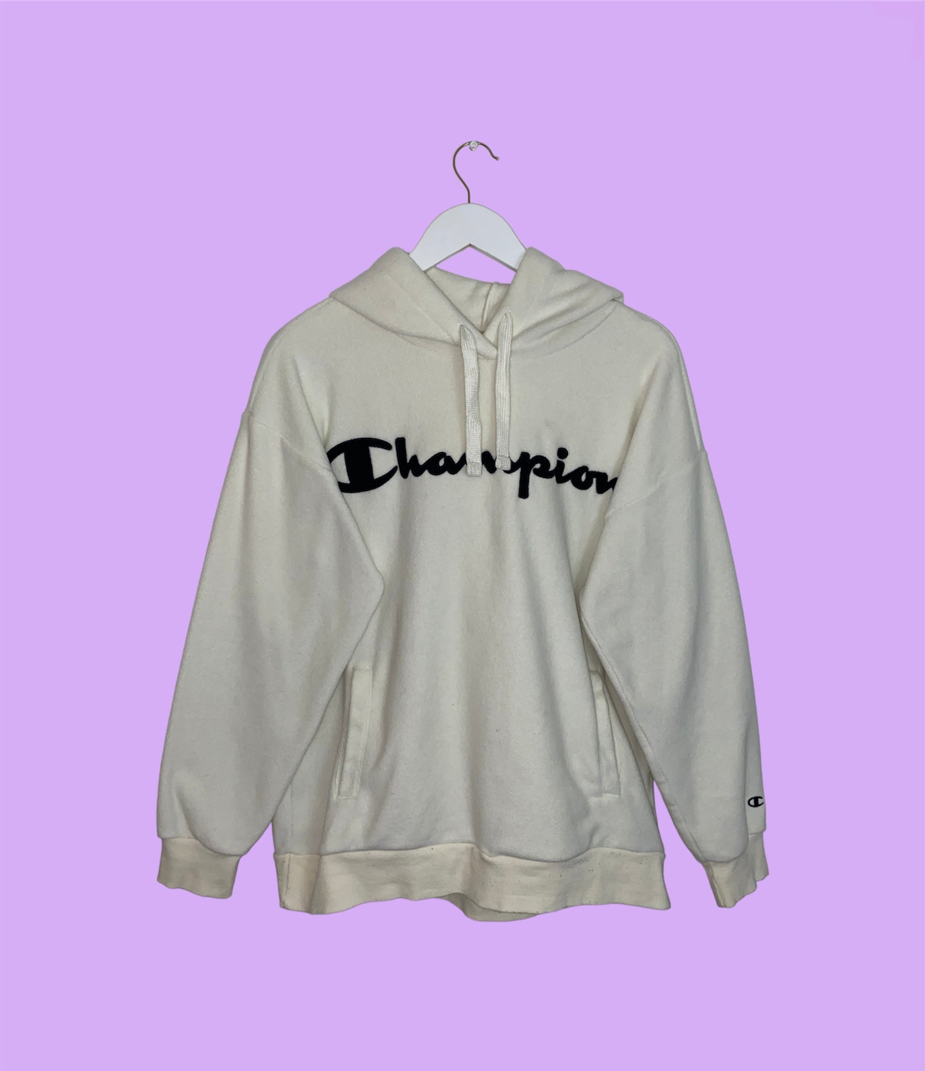 white hoodie with black big text champion logo shown on a lilac background