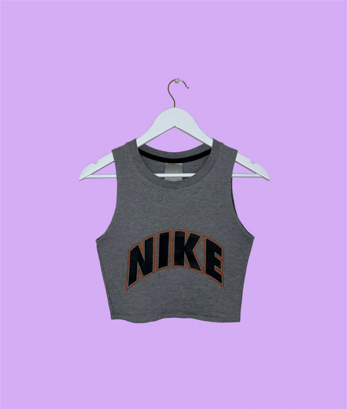 grey sleeveless crop top with orange and black nike logo shown on a lilac background