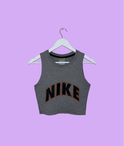 grey sleeveless crop top with orange and black nike logo shown on a lilac background