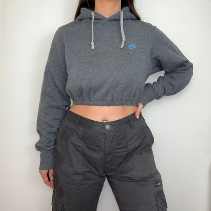 dark grey cropped hoodie with small blue nike logo shown on a model wearing grey cargo trousers with hand on hip