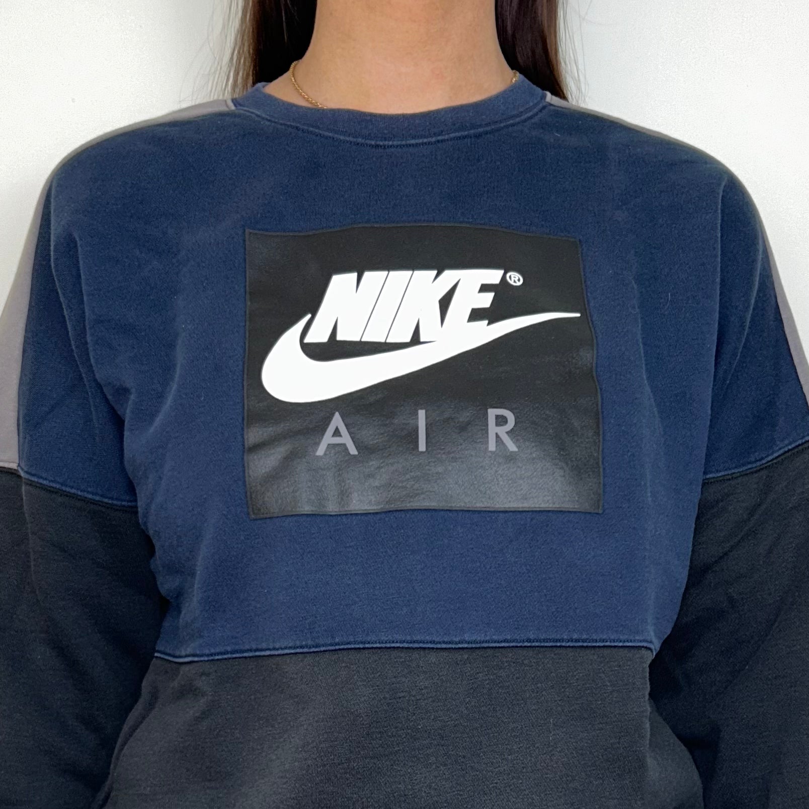 close up of black and navy sweatshirt with white nike logo shown on a model