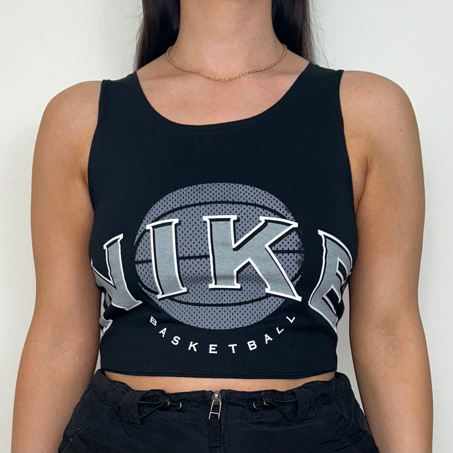 close up of black sleeveless crop top with grey nike logo shown on a model