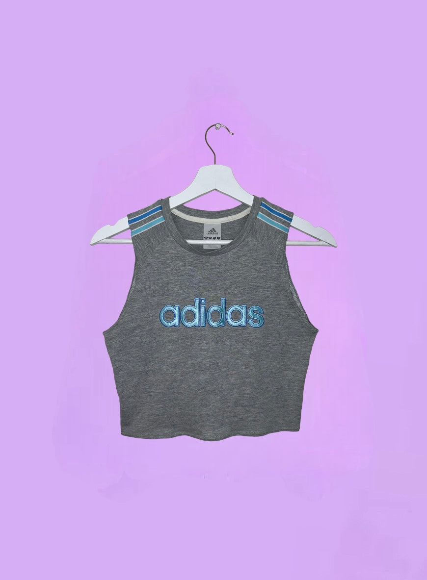 grey short sleeve crop top with light blue adidas logo shown on a lilac background