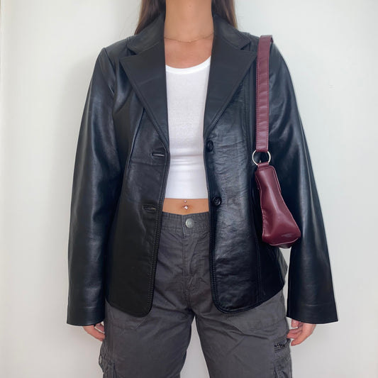 black real leather blazer jacket shown on a model wearing a white crop top and grey cargo trousers with a burgundy shoulder bag