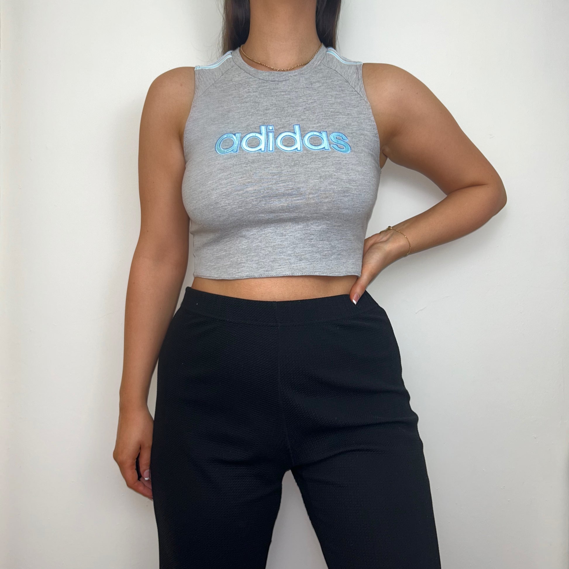 grey short sleeve crop top with light blue adidas logo shown on a model wearing black trousers