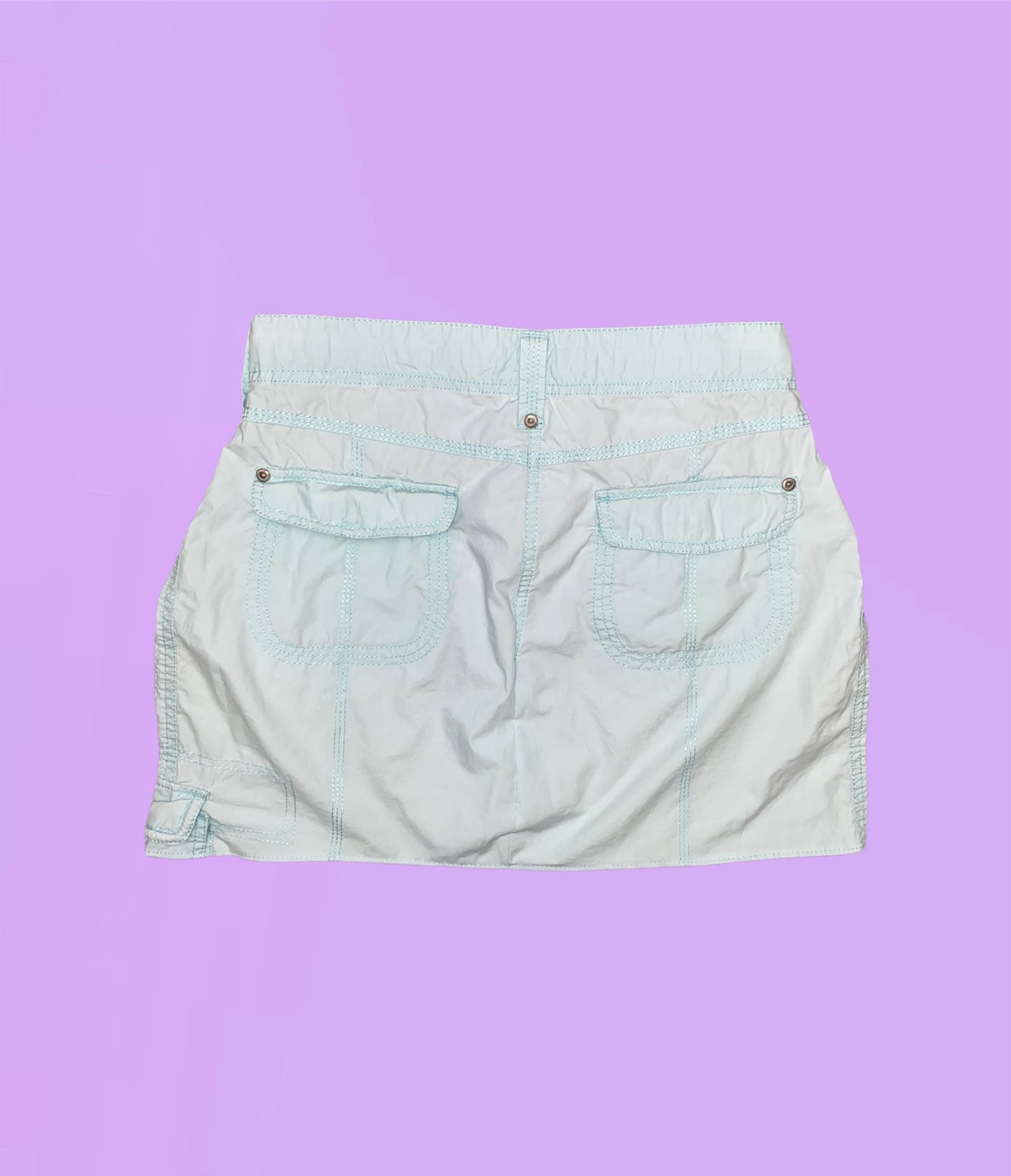 back of a light blue mini cargo skirt shown on a lilac background
