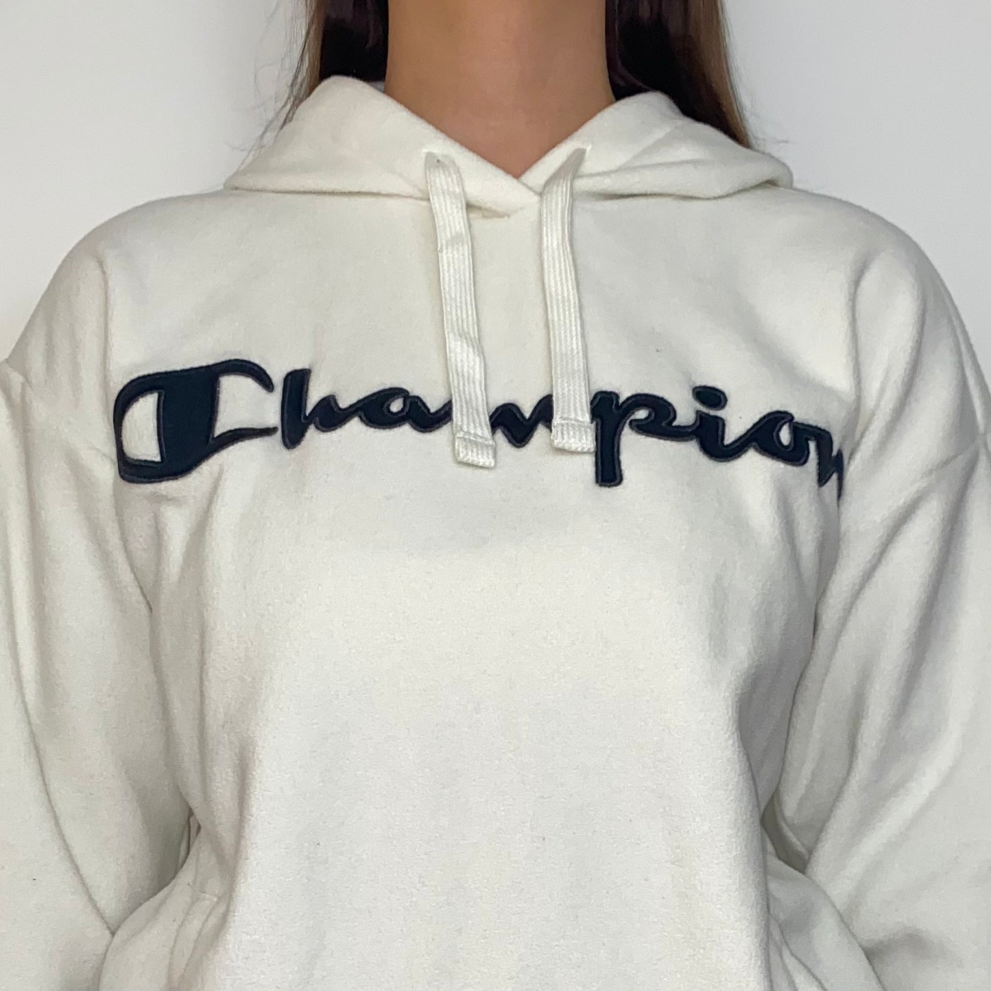 close up of white hoodie with black big text champion logo shown on a model