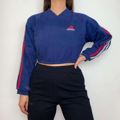 navy cropped sweatshirt with red adidas logo shown on a model wearing black trousers with hand on hip