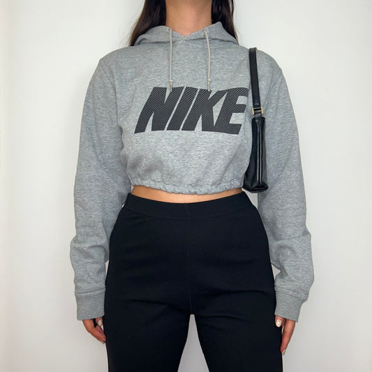 grey cropped hoodie with black nike logo shown on a model wearing black trousers and a black shoulder bag