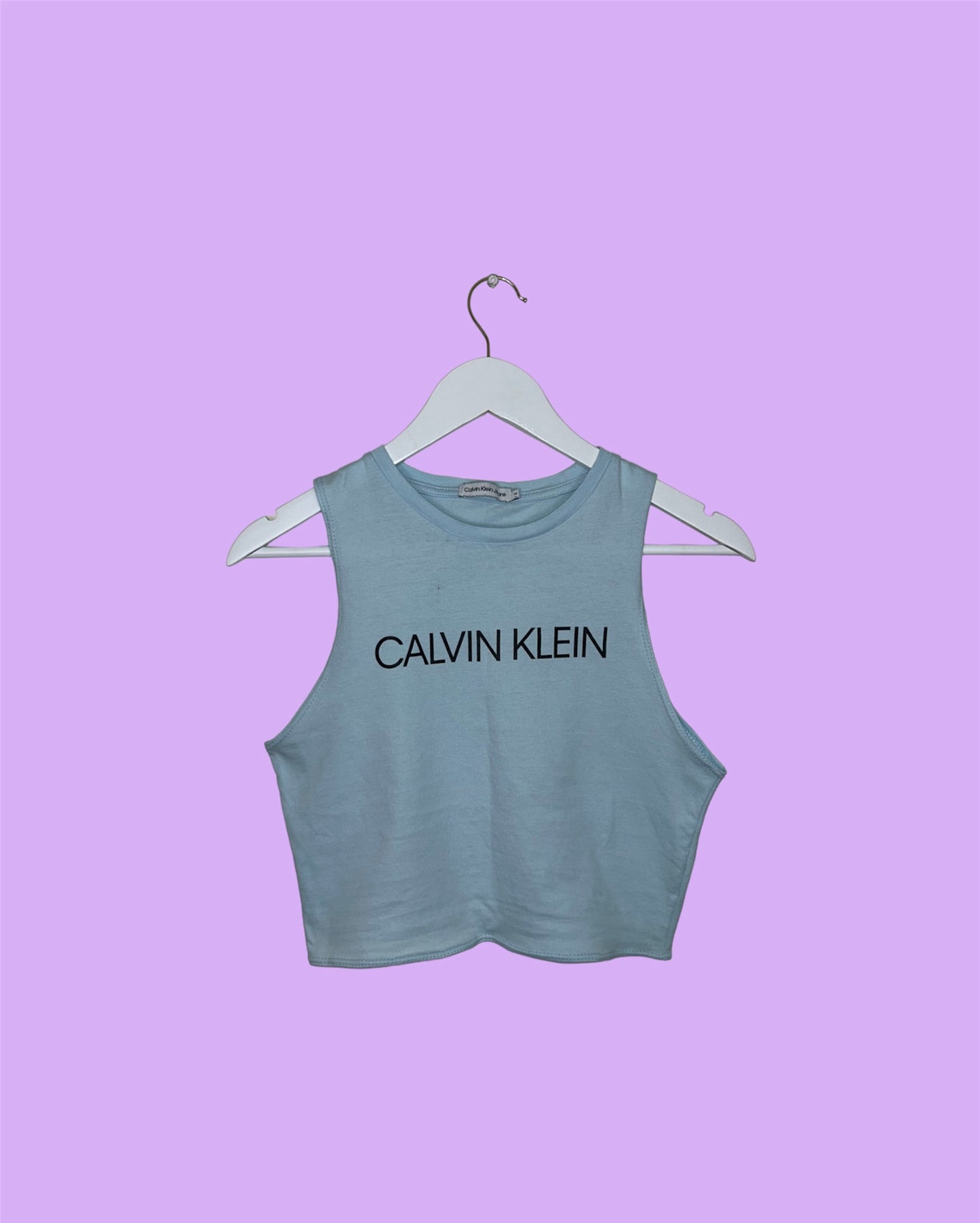 baby blue sleeveless crop top with black calvin klein logo shown on a lilac background