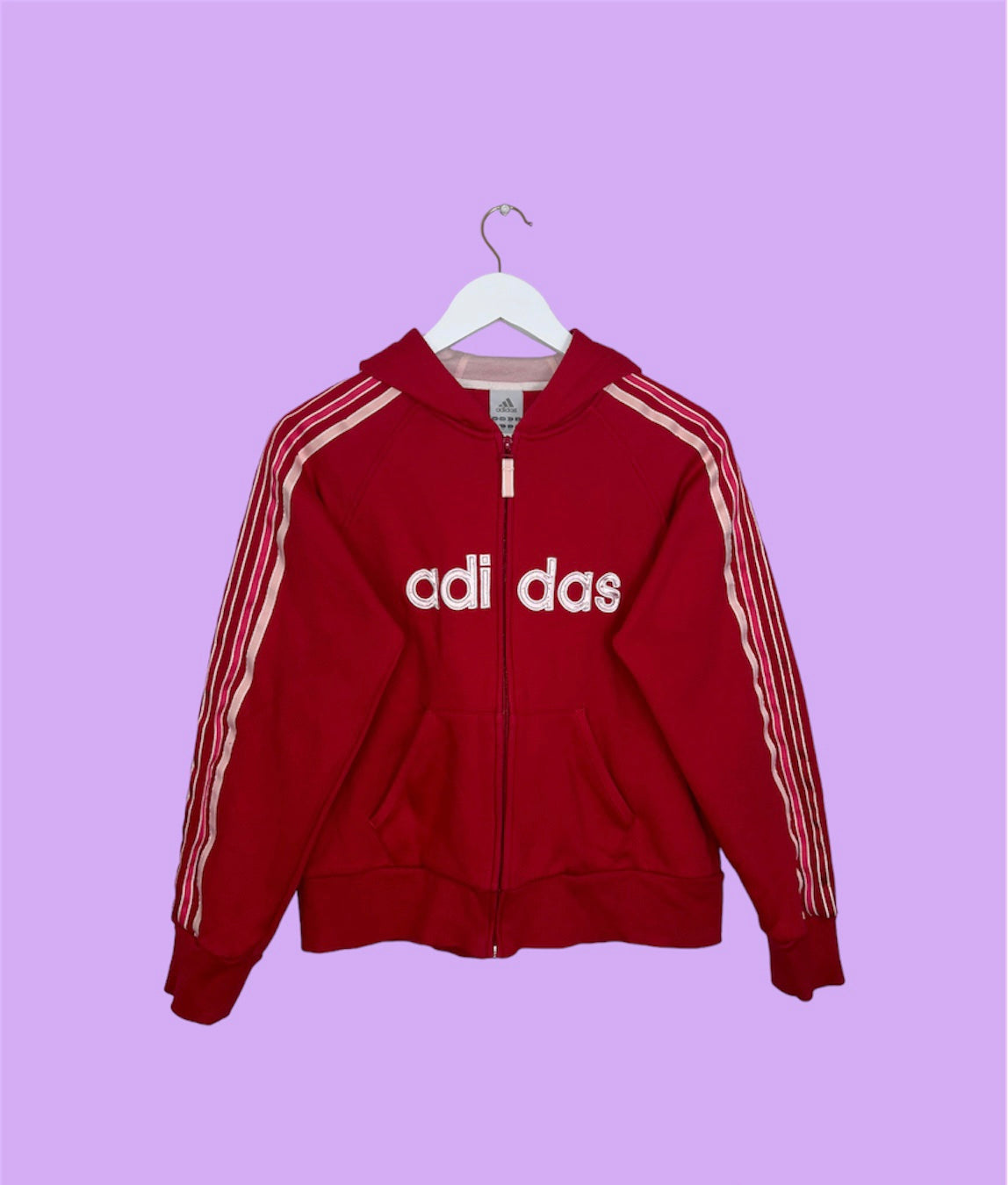 red zip up hoodie with big adidas text logo shown on a lilac background