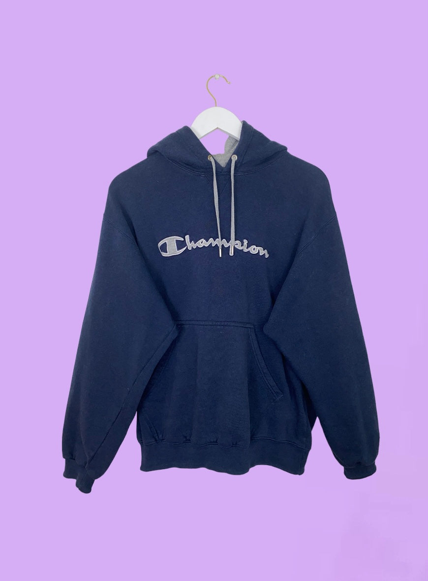 navy blue hoodie with big text champion logo shown on a lilac background