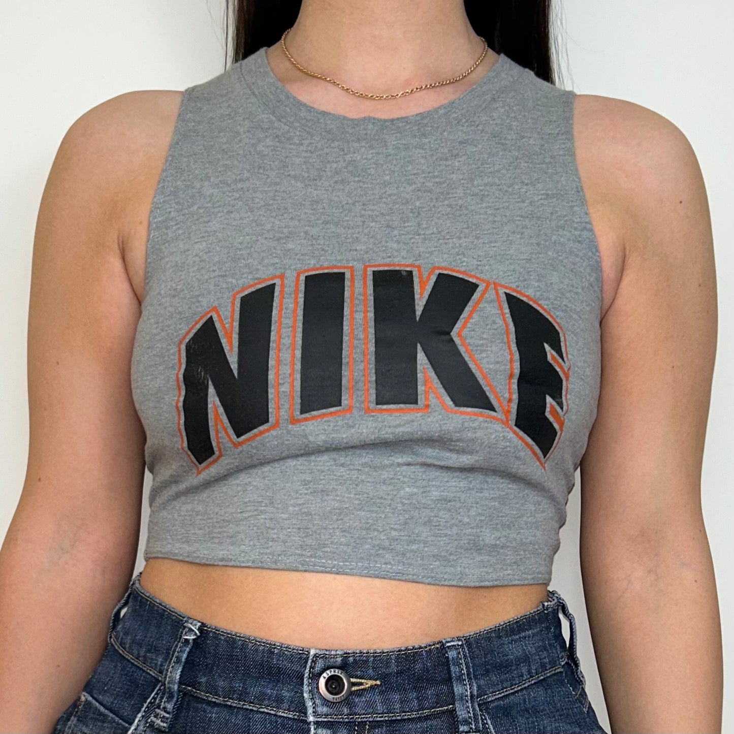 close up of grey sleeveless crop top with orange and black nike logo shown on a model